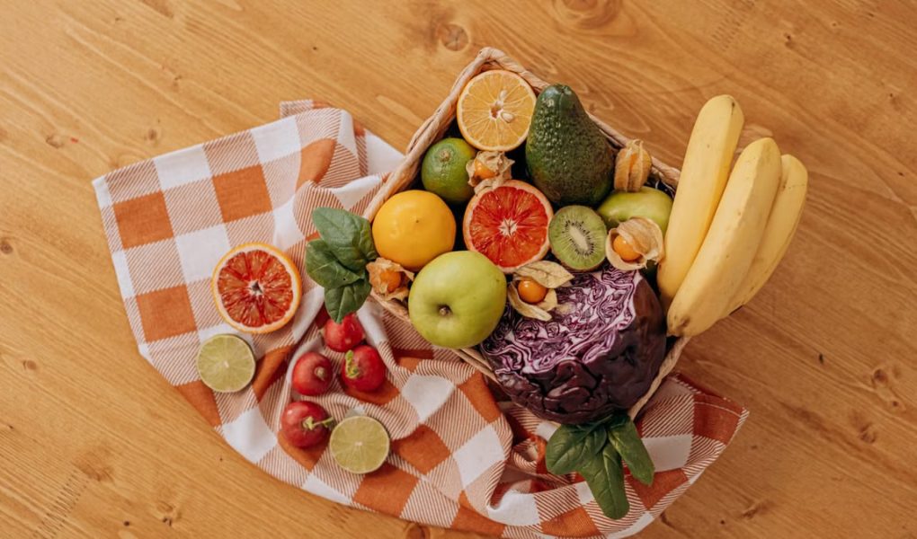 A vibrant flat lay of assorted fresh fruits on a checkered cloth over a wooden surface, perfect for healthy lifestyle concepts.