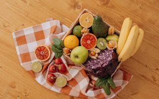 A vibrant flat lay of assorted fresh fruits on a checkered cloth over a wooden surface, perfect for healthy lifestyle concepts.